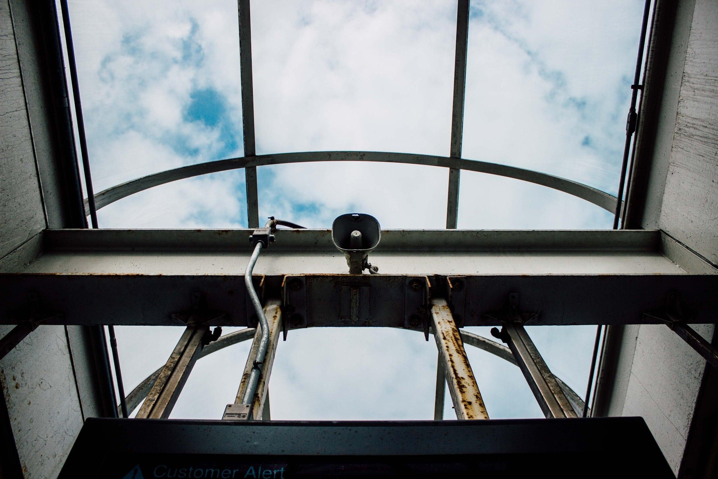 Commercial PA speaker and intercom system mounted on warehouse ceiling for emergency notifications
